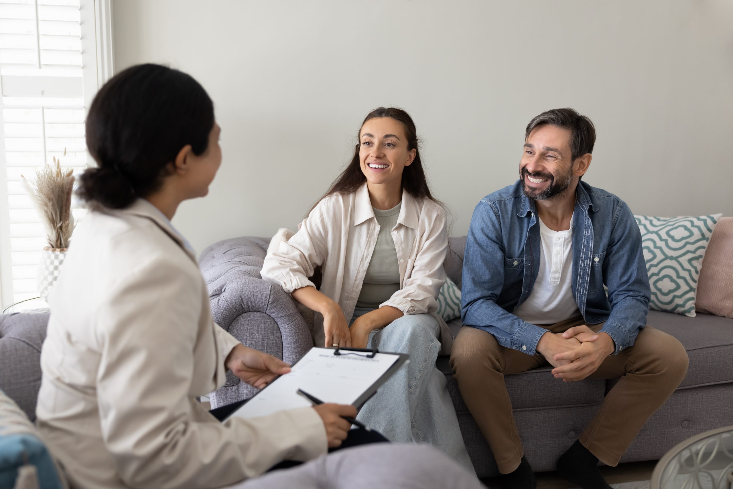 Happy couple of homeowners meeting with insurance agent at home